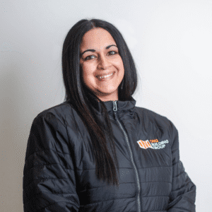 Amanda, Admin and Office Manager at ONQ Building Group, smiling in a branded black jacket, showcasing commitment to quality service and teamwork in home renovations.